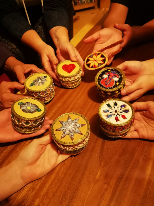 Group of hands holding quill boxes