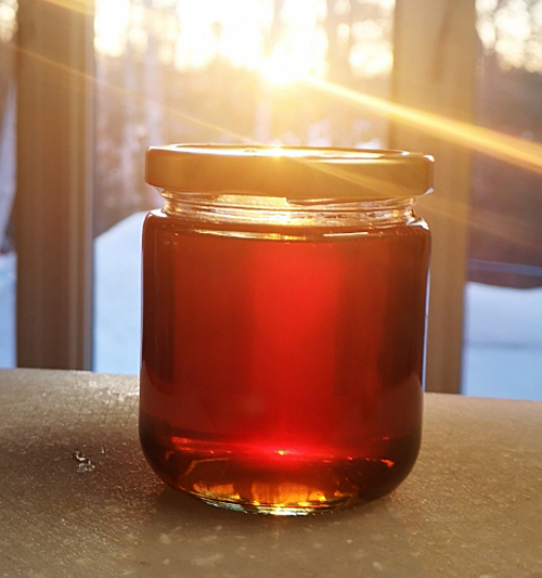 jar of honey in front of window with sunlight coming through it